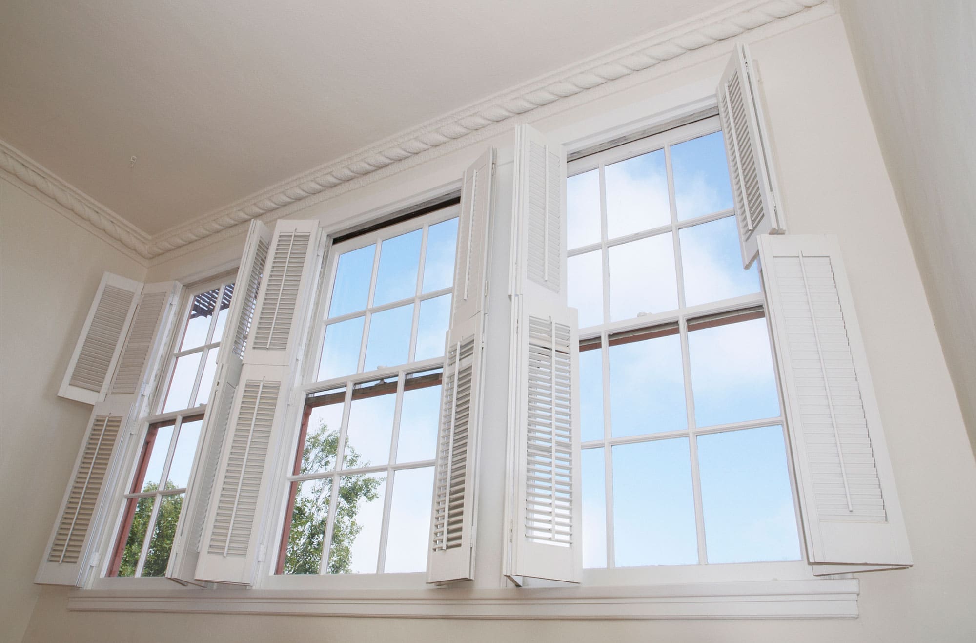White tier on tier shutters open to show blue sky outside