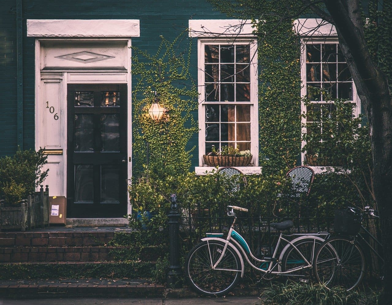 Exterior of a town house with shrubbery and a bicycle